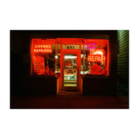 Neon-lit store window with repair services advertised at night.