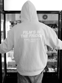 Person wearing a hoodie with text 'Film's in the Fridge' in Essential Photo Supply camera store setting