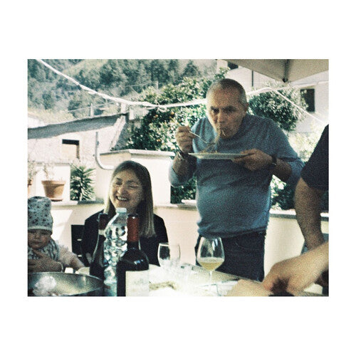 Family gathered around a table outdoors, enjoying a meal together.