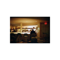 Dining area with patrons and a counter inside a restaurant, featuring an 'EXIT' sign.
