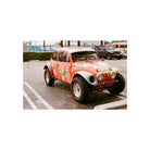 Vibrant orange Volkswagen Beetle with floral decals and off-road tires, captured on FLIC Film Elektra 100 color negative film.