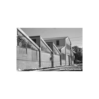 High-contrast black and white architectural shot of a brick warehouse with sharp detail and deep shadows.