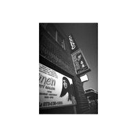 Low-contrast black and white 35mm film shot of a beauty salon sign on a brick building, showing fine grain and smooth detail.