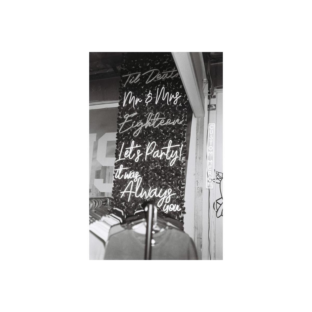Black and white film shot of neon script signs on a dark wall, capturing a moody, high-contrast aesthetic.