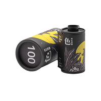 FilmNeverDie KURO 100 ISO 35mm black and white film canister and cylindrical cardboard packaging with yellow and black art.
