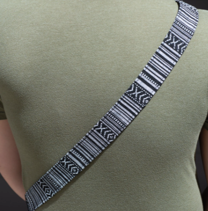 A camera strap with a multicolored pattern and black leather ends.