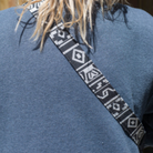 A camera strap with a multicolored pattern and black leather ends.