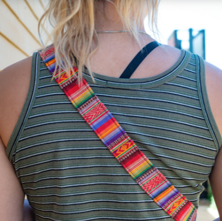 A camera strap with a multicolored pattern and black leather ends.