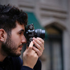 Man holding a camera up to his eye with a blurred background