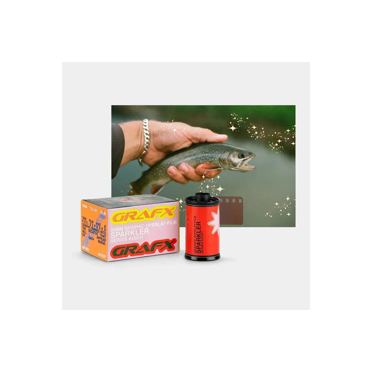 Grafx Sparkler 56mm color negative film shown with its orange and white retail box and a red film canister, alongside a sample of a fish photo edited with sparkly overlays and a small brown color card on a light gray background.