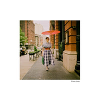 Woman in a plaid dress and red parasol walking on a city sidewalk, captured with HARMAN Phoenix II 200 color film.
