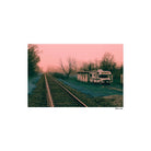 Vintage RV parked near train tracks with a pinkish sky