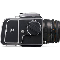 A black and silver Hasselblad 500Cw medium format camera with an attached black lens, shown from a side profile on a white background.
