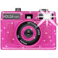 Hot pink Holga 135FC toy camera with a glittery finish, built-in flash, and a 47mm optical lens on a white background.