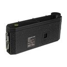 A black textured exposure guide camera accessory with a circular dial, a small green indicator light, and a printed exposure chart label on the side, shown against a plain white background.