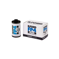 An Ilford FP4 Plus black and white film canister standing next to its white retail box on a clean white background.