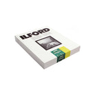 A boxed Ilford photo paper pack shown at an angle on a plain white background. The white box features the Ilford logo in black, a black-and-white sample photograph, and a green-and-yellow paper strip wrapped around the side.