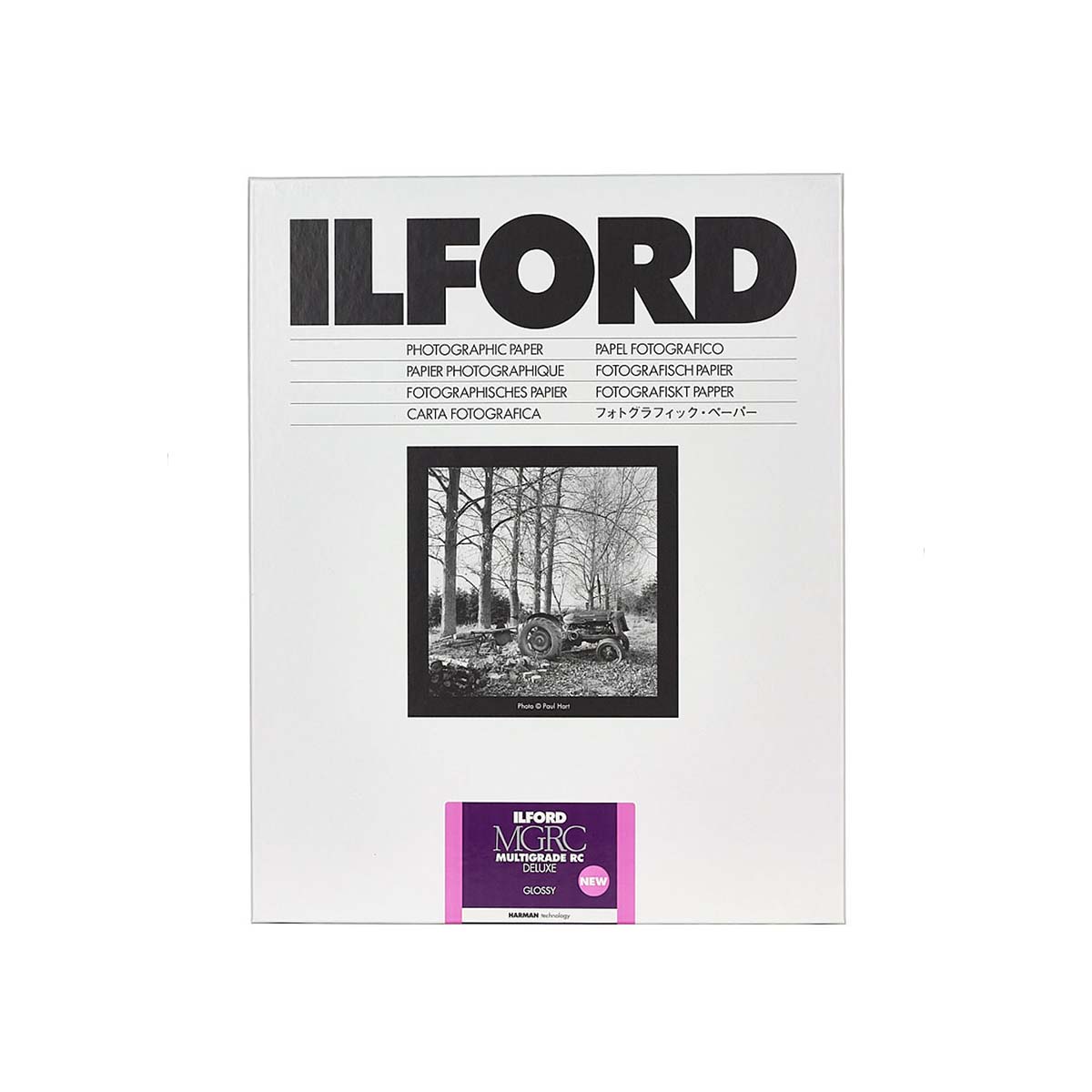 A pack of Ilford Fine Grainphotographic paper, featuring a white package with black text, a black-and-white sample photo of a tractor in a forest, and a purple Multigrade Glossy label at the bottom.