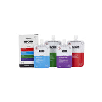 ILFORD Simplicity starter pack containing four liquid pouches in blue, green, purple, and red, displayed next to their retail box on a white background.