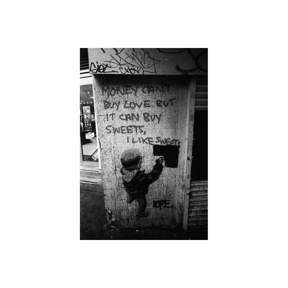 High-contrast black and white street photography showing graffiti of a child painting on a wall with text.