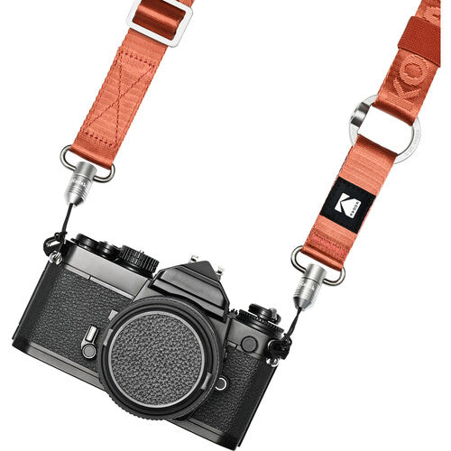 Orange Kodak multipurpose camera strap with quick-detach buckles and silver hardware attached to a black vintage camera.