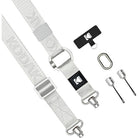 A Kodak camera strap in light gray with silver metal hardware, shown alongside a black branded keeper, a carabiner, and two small silver tools on a plain white background.