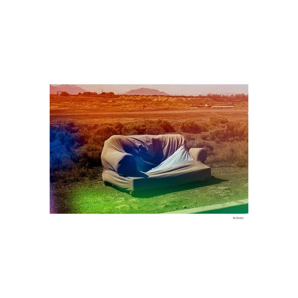 A couch in a desert landscape featuring KONO! Galaxy 200 film's signature multicolored light leaks and color shifts.