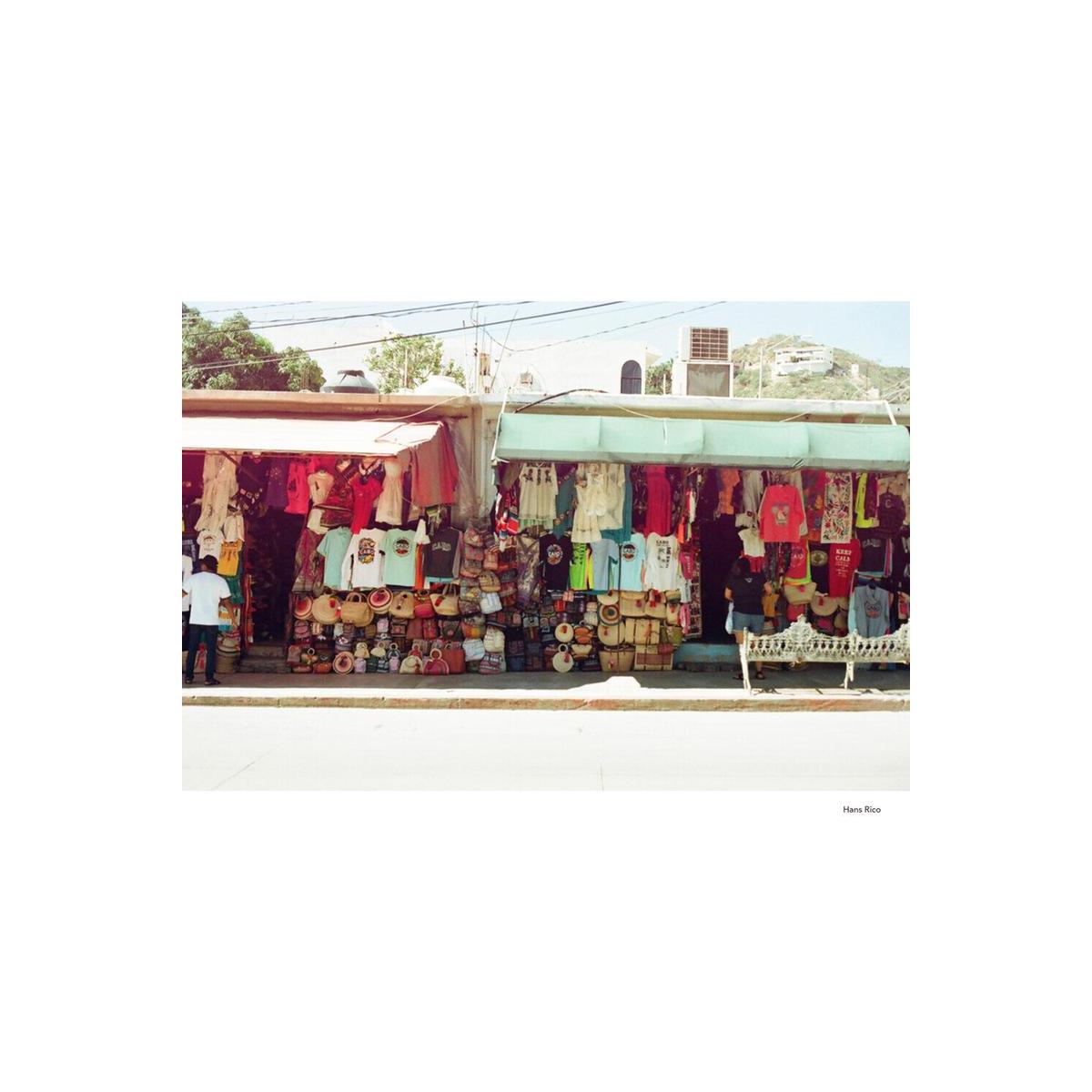 Street market stalls with colorful clothing and woven bags captured in warm, soft tones on KONO! Mirage 200 35mm film.