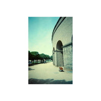 Street scene with stone arches, captured on 35mm film with moody, cool-toned colors and experimental film grain effects.