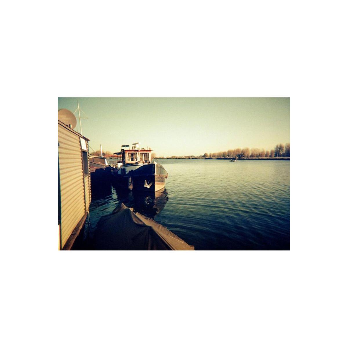 Boats docked on a calm river, captured with KONO! Moonstruck 200 film's signature muted, vintage color tones.