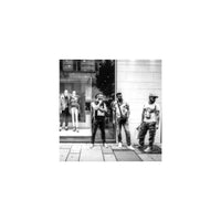 High-contrast black and white street photography shot on KONO! Rekorder film showing three men standing by a storefront.