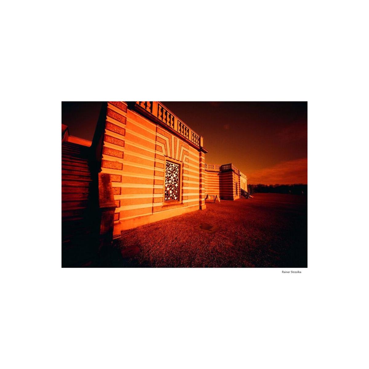 Architectural building with bold redscale film effect, featuring warm orange and amber tones and high-contrast shadows.