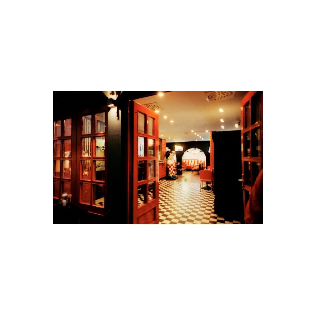 Interior view of a retro diner with red accents and checkered floors, captured on KONO! Smile 200 35mm color film.