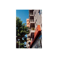 Low-angle shot of a modern apartment building with orange accents and a blue sky, captured on KONO! Smile 200 color film.