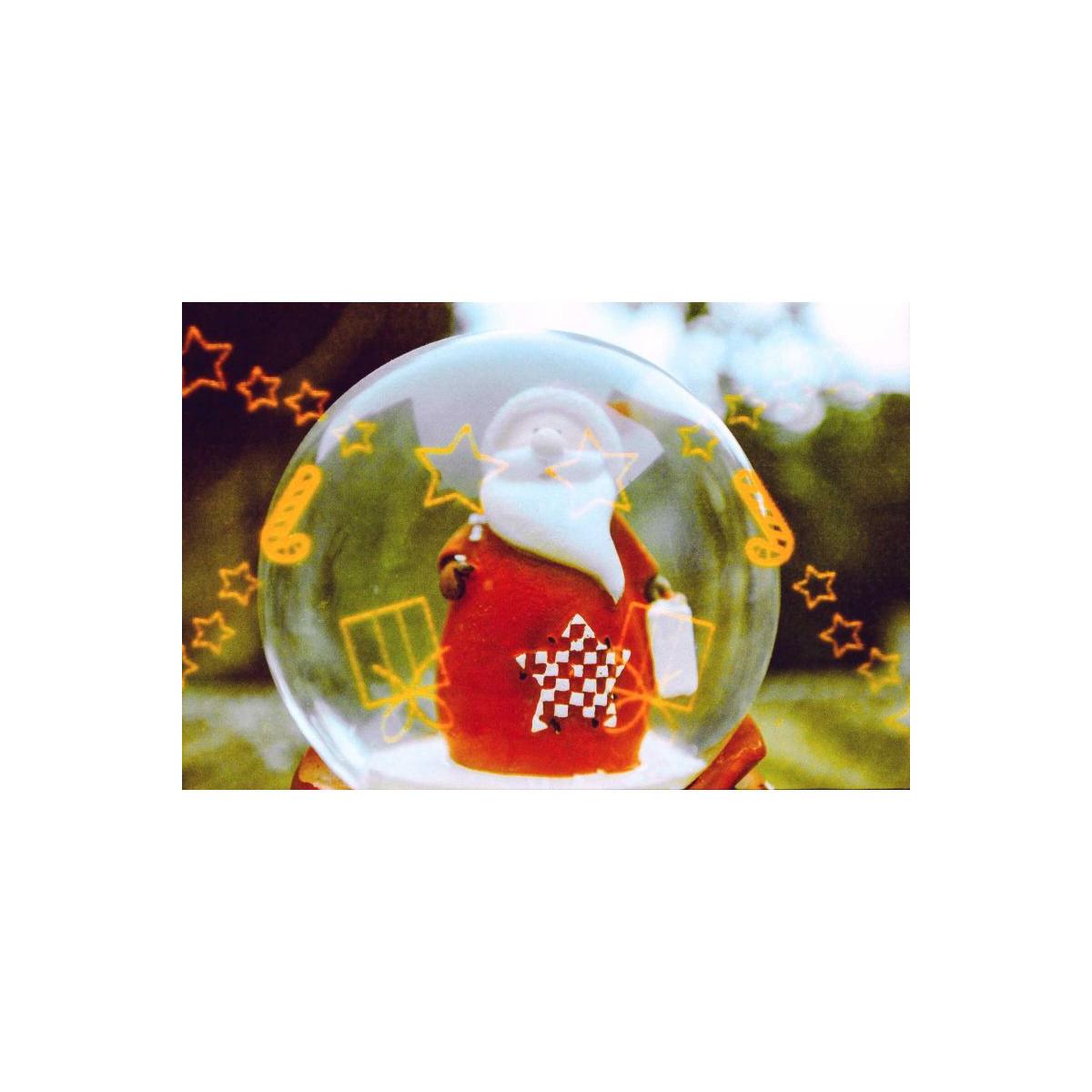 A clear glass snow globe featuring a small Santa Claus figure in a red suit with a white beard, surrounded by yellow star and gift graphics, set against a blurred outdoor background.