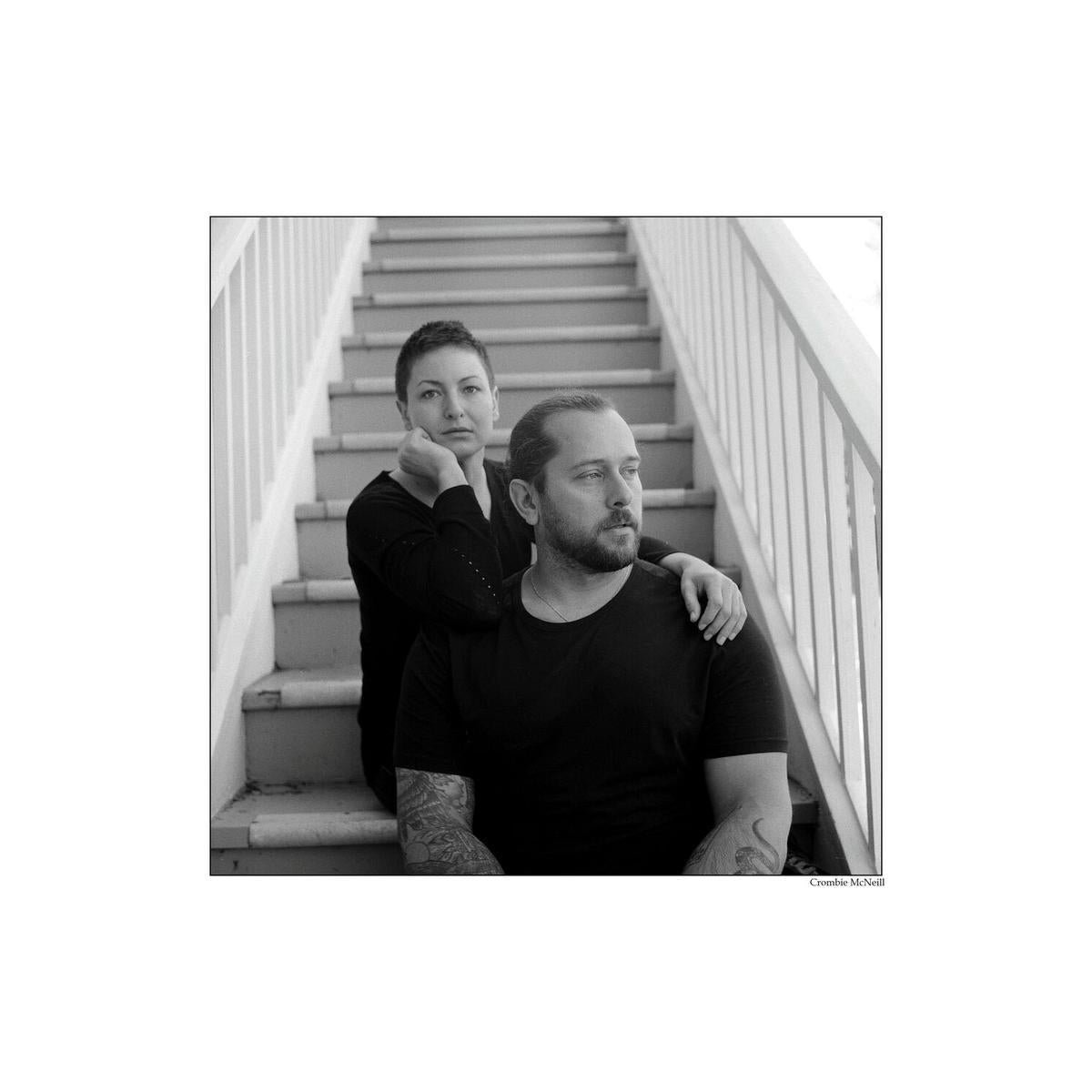 Black and white portrait of a couple sitting on stairs, captured with fine-grain Kentmere Pan 100 120 film.
