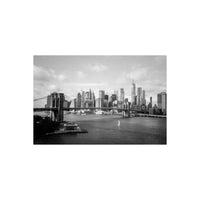 Black and white film photograph of the Brooklyn Bridge and Manhattan skyline with a sailboat on the East River.