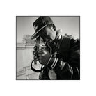 Black and white image of a man with a ball cap look thru a vintage camera with twin lenses