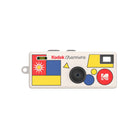 Kodak Charmera keychain digital camera with a white body, retro geometric patterns, and a central lens.