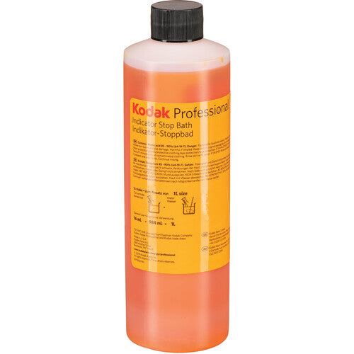 A bottle of Kodak Professional Indicator Stop Bath liquid with orange liquid inside, a yellow label, and a black cap, shown on a white background.