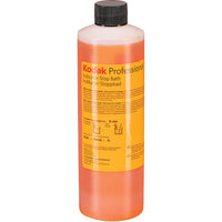 A bottle of Kodak Professional Indicator Stop Bath liquid with orange liquid inside, a yellow label, and a black cap, shown on a white background.