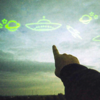 A person's hand pointing upward at a large projection of neon green cartoon drawings of planets, a spaceship, and a rocket on a cloudy sky background.