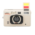A retro-style beige compact camera by Lomo Apparatus, featuring a black lens housing, red brand lettering, and a yellow-and-red viewfinder window on a plain white background.