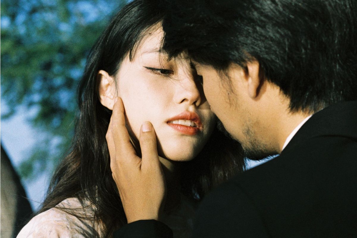 Two people close together with a blurred outdoor background