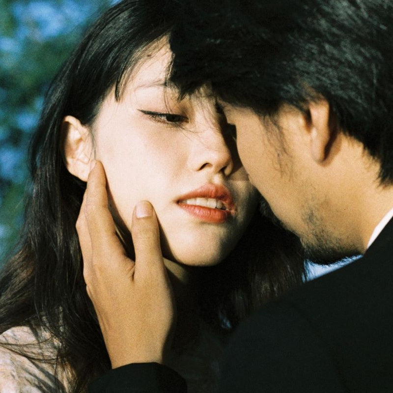 Two people close together with a blurred outdoor background