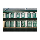 Person standing in front of a building with green windows
