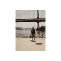 Skater on a waterfront path with a bridge in the background, captured in warm, vintage-toned 120 film style.
