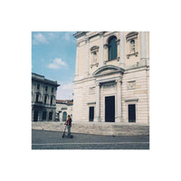Person on an electric scooter in front of a historic stone cathedral, captured with warm, vintage film aesthetics.