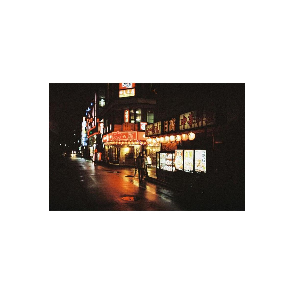 Night street scene with muted, desaturated colors and gritty grain captured on LomoChrome Metropolis 110 film.