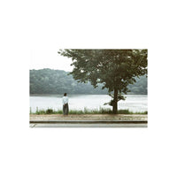Person standing by a lake with desaturated, gritty tones typical of LomoChrome Metropolis 110 film.